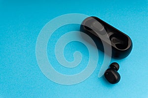 Wireless earbuds or earphones on blue background. Copy space