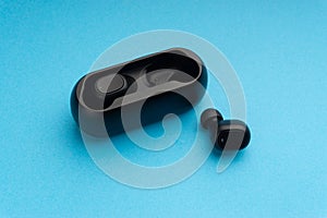 Wireless earbuds or earphones on blue background. Copy space