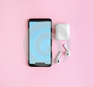 Wireless earphones, mobile phone and charging case on pink background. Space for text