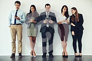 Wireless entertainment while they wait. Studio shot of a group of businesspeople using wireless technology while