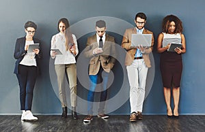 Wireless entertainment for the wait. Studio shot of a group of businesspeople using wireless technology while waiting in