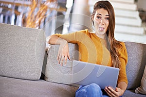 Wireless fun. an attractive young woman relaxing on the sofa with her laptop.