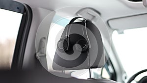 The wireless headphones of the car's entertainment multimedia system hang on the driver's seat.