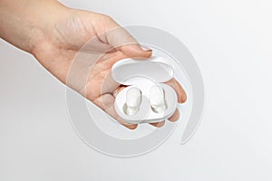 Wireless headphones in a charger in a female hand on a white background