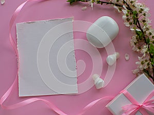 Wireless headphones on pink background with cherry flowers and copy space