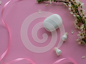 Wireless headphones on pink background with cherry flowers and copy space