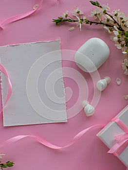 Wireless headphones on pink background with cherry flowers and copy space