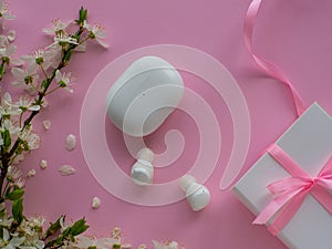 Wireless headphones on pink background with cherry flowers and copy space