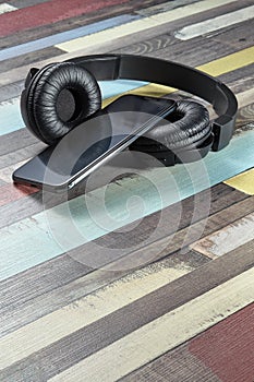 Wireless headphones and smartphone. Modern powerful black wireless headphones and smartphone on a wooden surface of