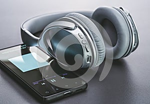 Wireless headphones and smartphone, studio shot with shadow on background with light. Modern devices for listening to music.