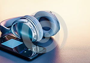 Wireless headphones and smartphone, studio shot with shadow on background with light. Modern devices for listening to music.