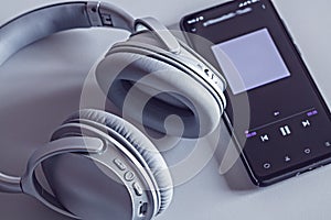 Wireless headphones and smartphone, studio shot with shadow on background with light. Modern devices for listening to music.