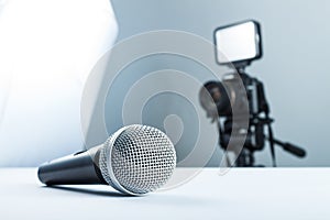 A wireless microphone lying on a white table against the background of the DSLR camera to led light