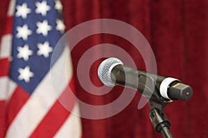 Wireless microphone on stand with American flag in the background.