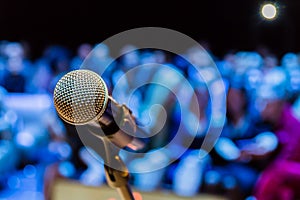 Wireless microphone on the stand. Blurred background. People in the audience. Show on stage in the theater or concert hall