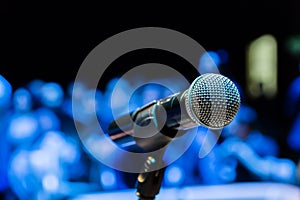 Wireless microphone on the stand. Blurred background. People in the audience. Show on stage in the theater or concert hall