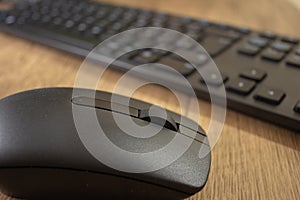 Wireless mouse and keyboard set on top of a wooden office desk, on a workstation