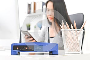 Wireless router and woman using a smartphone  in office. router wireless broadband home laptop computer phone wifi concept