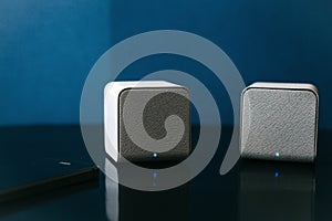 Wireless speakers and a cell phone next to them on a dark background. Modern technology for listening to music from a