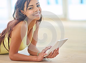 Wireless and stressless. a young woman using a digital tablet while lying on the floor at home.