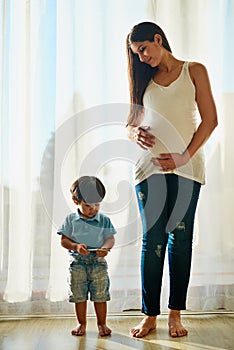 Wireless technology makes a great babysitter. a pregnant woman looking at her little boy while he plays with a