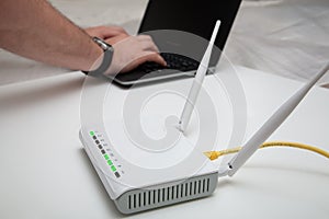 Wireless WiFi modem router network hub on white table. Blured men works on the computer on the background, with wireless internet