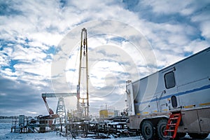 Wireline equipment hanging from top drive ready to be lowered downhole for logging. An oil well engineer works from the