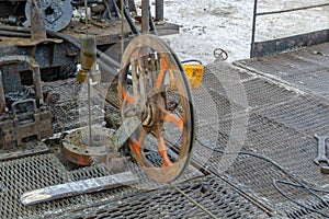 Wireline equipment hanging from top drive ready to be lowered downhole for logging. An oil well engineer works from the back of