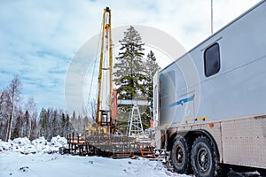 Wireline equipment hanging from top drive ready to be lowered downhole for logging. An oil well engineer works from the