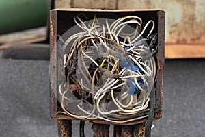 Wires interconnected in a rusty old crowded box for wires.