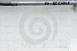 A wiring pipe tube of a cable EV car charnger on the cement wall of the frence