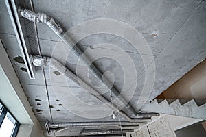 Wiring of ventilation pipes on a concrete ceiling in a house under construction