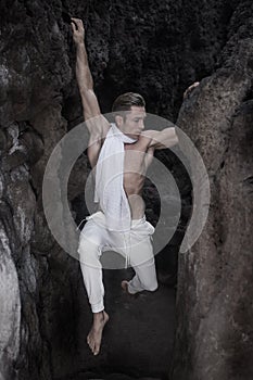 Wiry man stretching holding on to walls of gorge