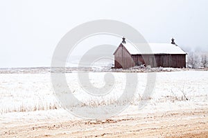 Wisconsin weathered barn next to trees and field covered with snow and frost