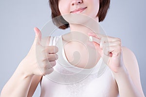 Wisdom teeth extraction, happy woman with tooth in hand on gray background