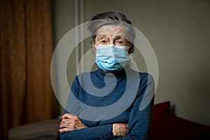 Wise look of old woman with medical mask encourages you to keep your distance and use protective equipment, health safety during