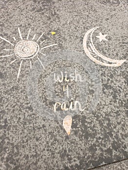 Wish for rain text on sidewalk with chalk and raindrops