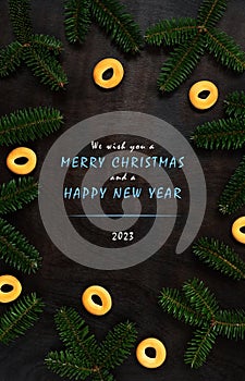We wish you a Merry Christmas and a Happy New Year 2023. Branches on the background of a wooden table