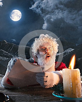 Emotional Santa Claus congratulating with New Year and Christmas, sending a letter, wish list in midnight with candle