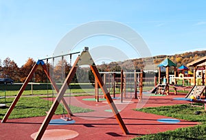 Wisniowa, Poland - oct 12 2018: Children`s playground in the park amidst greenery. Multicolored swings and buildings for children photo
