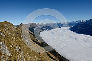 Wispy clouds cascading down the rugged slopes of a mountain range at Bernese Highlands