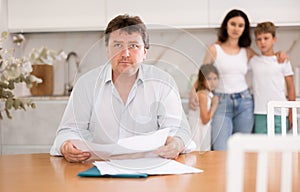 Wistful father looking through papers sitting in the kitchen