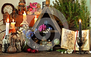 Witch altar table with magic book, flowers and spiritual objects