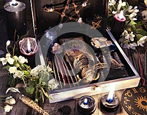 Witch box with black candles, tarot cards, runes, voodoo doll and magic objects with flowers