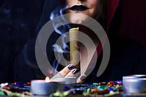 Witch hands performing a magic ritual blowing off a candle on a magical altar. Sorcerer rite of witchcraft