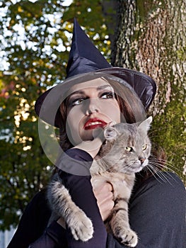 Witch holding cat outdoor.