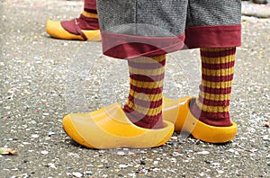 Witch legs in orange wooden shoes and striped socks.