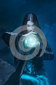 The witch with magic ball in her hands causes a spirits