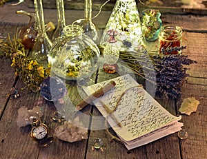 Witch manuscript with writings, magic bottles, crystals and lavender flowers on planks