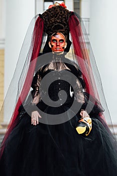 Witch portrait in black vintage dress. Woman widow with red art make-up for halloween.